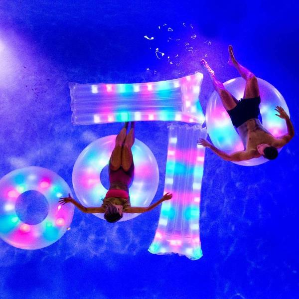 Man and woman floating in lighted pool floats